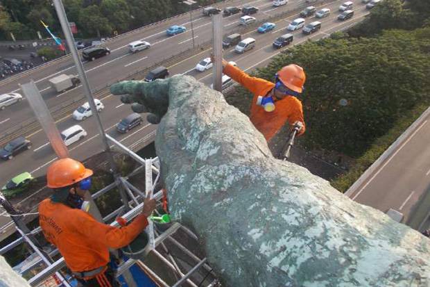 Petugas sedang mencuci bagian tangan Patung Dirgantara atau patung Pancoran. (Foto: Tim Garuda Adventure)