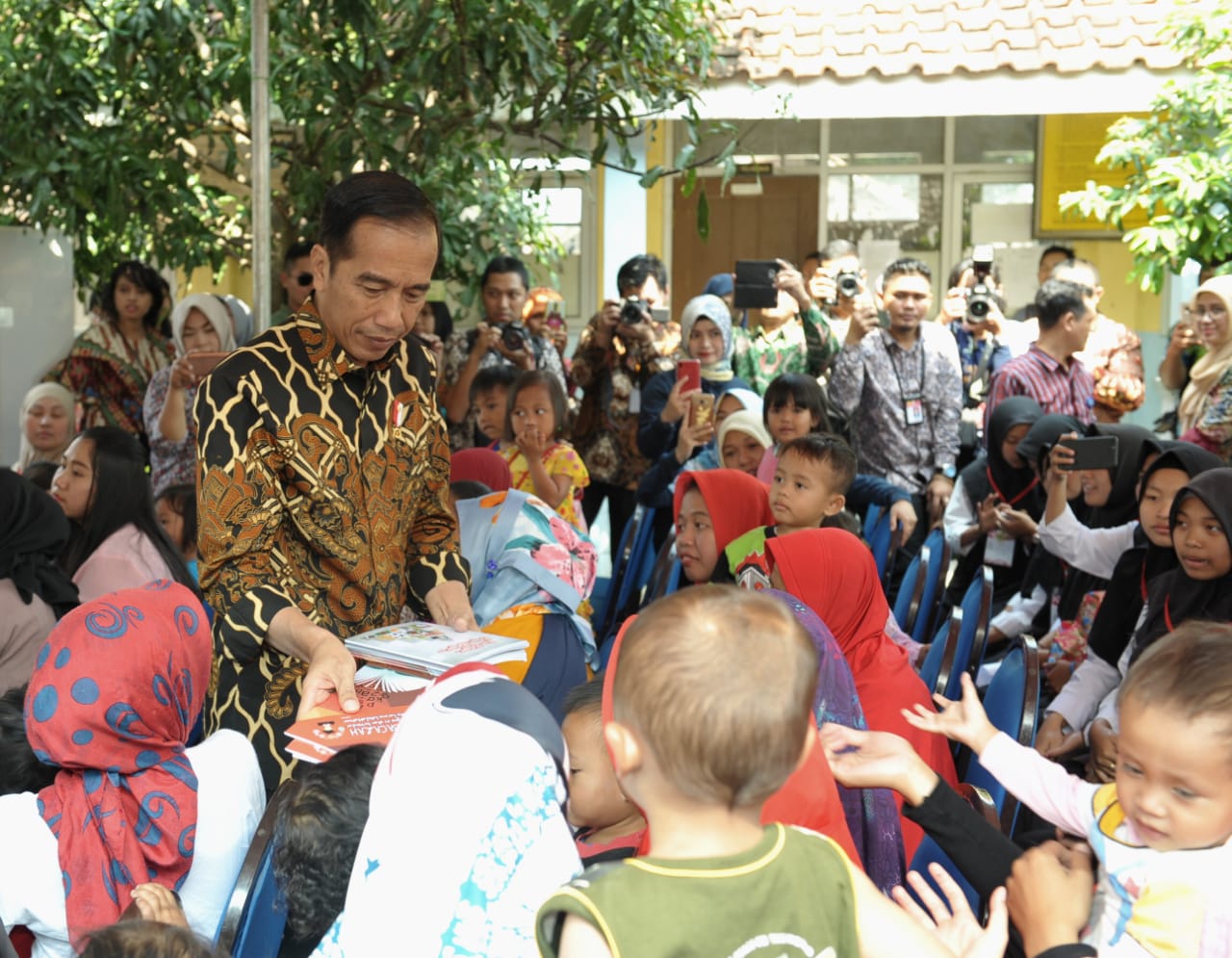 Presiden Jokowi dan Jim Yong Kim membagikan sejumlah buku tulis untuk anak-anak dan mencicipi penganan penambah gizi anak.